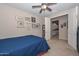 Cozy bedroom showcases blue bedding, decorative shelving, and open doorway to the adjacent kitchen area at 16409 W Alvarado Dr, Goodyear, AZ 85395