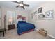 Serene bedroom featuring a blue quilted bed, wooden accents, and decorative wall shelving with photos at 16409 W Alvarado Dr, Goodyear, AZ 85395