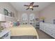 Comfortable bedroom with a ceiling fan, yellow quilted bedding, and natural light from two arched windows at 16409 W Alvarado Dr, Goodyear, AZ 85395