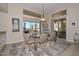 Bright dining area with a glass table, four chairs, and desert landscape views through large picture windows at 16409 W Alvarado Dr, Goodyear, AZ 85395