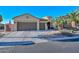 Attractive tan home featuring a two car garage, a circular tower feature, and desert landscaping at 16409 W Alvarado Dr, Goodyear, AZ 85395