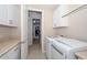 Well-organized laundry room with white cabinets, modern machines, and access to closet at 16409 W Alvarado Dr, Goodyear, AZ 85395