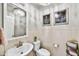 Stylish powder room with elegant lighting, decorative wall art, and a sleek pedestal sink at 17138 W Las Palmaritas Dr, Waddell, AZ 85355