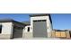 View of gray multi-car garage with carriage doors and exterior lighting on a sunny day at 17312 W Royal Palm Rd, Waddell, AZ 85355