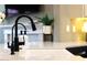 Close-up of a modern black faucet and sink, set against a backdrop of stylish countertops and a view of the living area at 20785 W Canyon Dr, Buckeye, AZ 85396