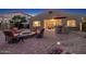 Dusk view of the backyard with outdoor kitchen, fire pit, brick pavers and lush landscape at 25609 N 54Th Ln, Phoenix, AZ 85083