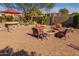 Inviting backyard patio with a fire pit, built in stone bar, and desert landscaping under sunny skies at 25609 N 54Th Ln, Phoenix, AZ 85083