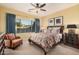 Comfortable bedroom features a ceiling fan, patterned bedding, and ample natural light from the large window at 25609 N 54Th Ln, Phoenix, AZ 85083