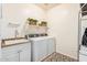 Well-lit laundry room with sink, shelving and white washer and dryer at 25609 N 54Th Ln, Phoenix, AZ 85083