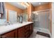 Elegant bathroom features a double sink vanity, a large glass shower, and warm color tones at 27108 W Escuda Dr, Buckeye, AZ 85396