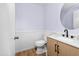 Powder room boasts wood-look floors, white wainscoting, round mirror and a wood vanity with black hardware at 28871 N Coal Ave, San Tan Valley, AZ 85143