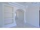 Open-concept living room with marble-like tile flooring, archway, and built in shelving at 3547 W Encanto Blvd, Phoenix, AZ 85009