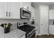 Close-up of gas range shows the modern white cabinetry, granite counters and stainless steel appliances at 38162 W Santa Monica Ave, Maricopa, AZ 85138