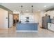 Modern kitchen with a center island, white cabinets, stainless steel appliances, and stylish pendant lighting at 40176 W Williams Way, Maricopa, AZ 85138