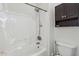 Bathroom shower and tub featuring white tile, a shower head, and a dark cabinet for storage at 4043 W Aire Libre Ave, Phoenix, AZ 85053