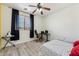 Bright bedroom features a ceiling fan, a window overlooking the neighborhood, and gray wood-look flooring at 4043 W Aire Libre Ave, Phoenix, AZ 85053