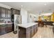 Modern kitchen with stainless steel appliances, a large center island, and views to the living and dining areas at 4043 W Aire Libre Ave, Phoenix, AZ 85053