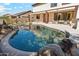 Lush backyard featuring a blue pool surrounded by gray rocks, seating, and landscaped plants at 4043 W Aire Libre Ave, Phoenix, AZ 85053