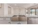 Close-up of a stainless steel farmhouse sink in a kitchen with granite countertops and white cabinets at 8553 N 175Th Ln, Waddell, AZ 85355