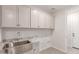 Convenient laundry room with sink, granite countertop, cabinet space, and utility connections at 8553 N 175Th Ln, Waddell, AZ 85355