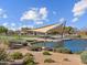 Outdoor seating area with shaded picnic tables by a serene pond and well-kept landscaping at 8554 W Trenton Ct, Florence, AZ 85132