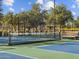 Well-maintained tennis court with green and blue surface, surrounded by fencing and trees with a wooden bench nearby at 8554 W Trenton Ct, Florence, AZ 85132