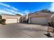 Well-maintained home showcasing a three-car garage and a paved driveway under a clear blue sky at 9360 E Milagro Ave, Mesa, AZ 85209