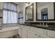 Bright bathroom featuring a double sink vanity with black countertops and elegant mirrors at 9404 W Pierson St, Phoenix, AZ 85037