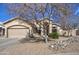 Beautiful home showcasing mature trees, attractive rock landscaping, and a two-car garage at 9404 W Pierson St, Phoenix, AZ 85037