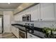 Kitchen with black countertops, white cabinetry, stainless steel appliances, and a subway tile backsplash at 9404 W Pierson St, Phoenix, AZ 85037