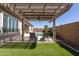 Relaxing backyard featuring a covered pergola with fan, artificial grass, and lounge chairs at 10657 E Evergreen St, Mesa, AZ 85207