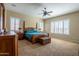 Bright bedroom featuring large windows with white shutters, a ceiling fan and wood furniture at 10657 E Evergreen St, Mesa, AZ 85207