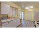 Well-lit kitchen boasting white cabinets, a double sink, and sliding door to the outside at 10701 W Mountain View Rd, Sun City, AZ 85351