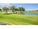 Scenic golf course view featuring a serene pond with water fountain and mature trees at 11413 E Neville Ave, Mesa, AZ 85209