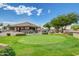 Beautiful putting green area with golf carts and clubhouse under a blue sky at 11413 E Neville Ave, Mesa, AZ 85209