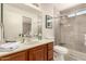 Bathroom featuring a tiled shower with a glass door, a wooden vanity with a white sink, and light neutral decor at 11830 S Paiute St, Phoenix, AZ 85044