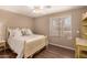 Cozy bedroom with wood floors, ceiling fan, a cream-colored bed and desk, and window with lots of natural light at 11830 S Paiute St, Phoenix, AZ 85044