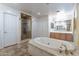 Bright bathroom featuring a shower, standalone tub, and wooden cabinets providing ample storage space at 12925 W Llano Dr, Litchfield Park, AZ 85340