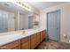 Bathroom featuring wood cabinets, a large vanity mirror, and a separate room for the shower at 12925 W Llano Dr, Litchfield Park, AZ 85340