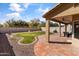 Covered patio with outdoor seating overlooks the backyard with rock and grass landscaping and block fence at 14309 W Weldon Ave, Goodyear, AZ 85395