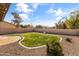 Wide view of the backyard with rock landscaping, grass, a concrete patio, and a block fence at 14309 W Weldon Ave, Goodyear, AZ 85395