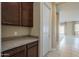 A hallway with a white door, dark cabinets, granite countertops, and views into an adjacent room at 14762 W Georgia Dr, Surprise, AZ 85379