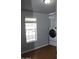 Laundry room with gray walls, wood floor, window, and stacked washer and dryer at 17016 N 66Th Ter, Glendale, AZ 85308