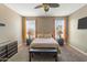 Neutral bedroom with a ceiling fan, carpet flooring, and two large windows for natural light at 18382 N Arbor Dr, Maricopa, AZ 85138