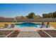 Backyard swimming pool featuring a basketball hoop, water feature and poolside lounge chairs at 21717 W South Mountain Ave, Buckeye, AZ 85326