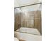 Bathroom with bathtub and shower showcasing a sliding glass door and wood-look tile surround at 24942 S 190Th Dr, Buckeye, AZ 85326