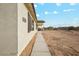 Exterior side view of a stucco home with desert landscaping and concrete walkway leading to the entrance at 24942 S 190Th Dr, Buckeye, AZ 85326