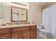 Bathroom with wood vanity, granite counters, framed mirror, and bathtub with striped shower curtain at 2625 W Oakland St, Chandler, AZ 85224