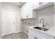 Bright laundry room with white cabinets, granite counters, and stainless steel sink at 32815 N Slate Creek Dr, San Tan Valley, AZ 85143