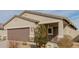 Angle view showcasing the two-car garage and stucco exterior with stone accents and desert landscaping at 35374 W San Sisto Ave, Maricopa, AZ 85138